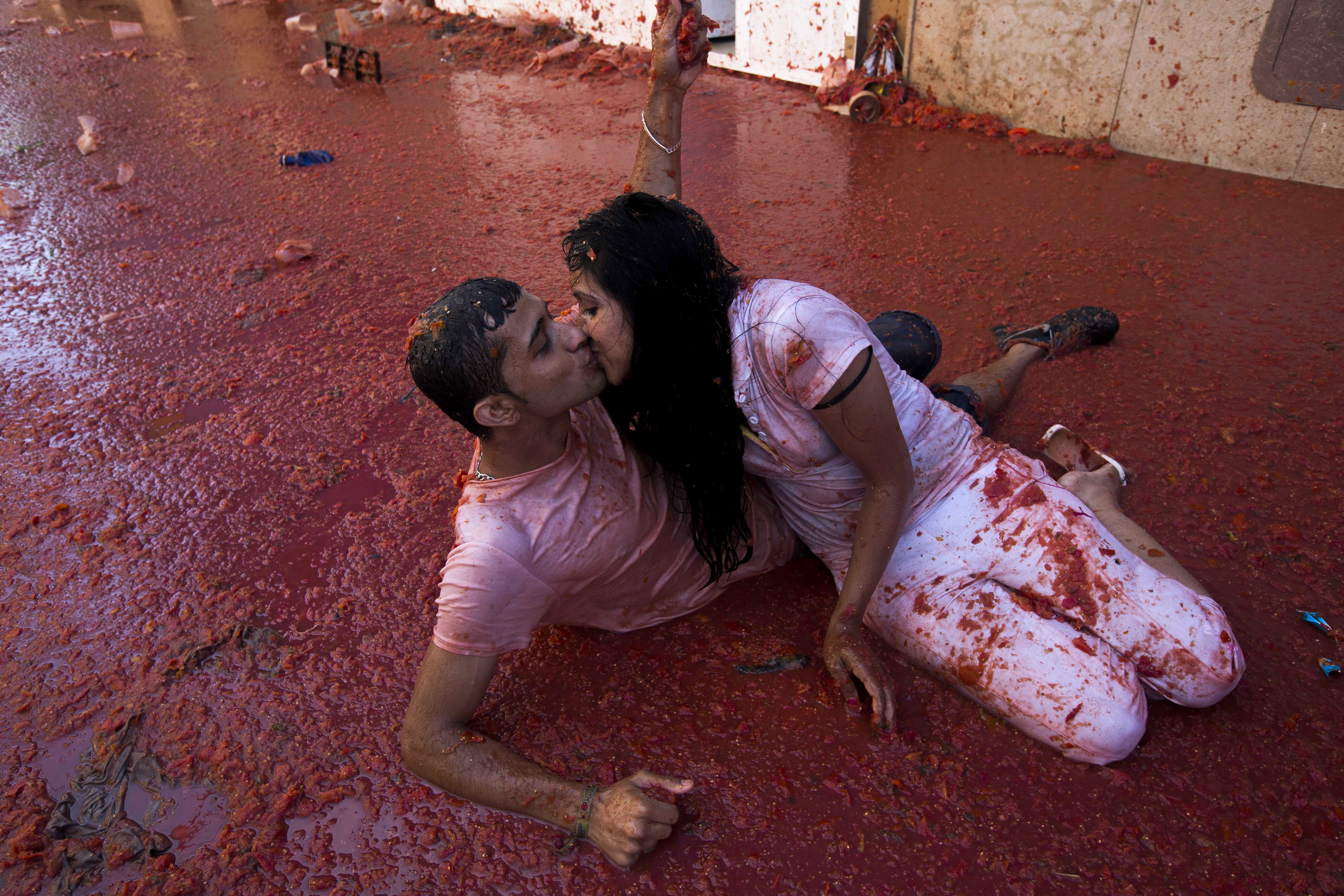 A couple kisses during the annual "tomatina" festivities in the village of Bunol, near Valencia on August 27, 2014. Some 22,000 revellers hurled 130 tonnes of squashed tomatoes at each other drenching the streets in red in a gigantic Spanish food fight known as the Tomatina. AFP PHOTO / GABRIEL GALLO