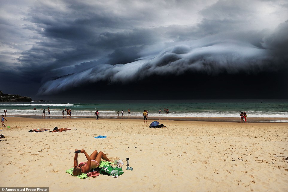In this image released by World Press Photo titled "Storm Front on Bondi Beach" by photographer Rohan Kelly for the Daily Telegraph which won first prize in the Nature singles category shows a massive cloud tsunami looming over Sydney as a sunbather reads, oblivious to the approaching cloud on Bondi Beach, Sydney, Australia, Nov. 6, 2015. (Rohan Kelly/Daily Telegraph, World Press Photo via AP)