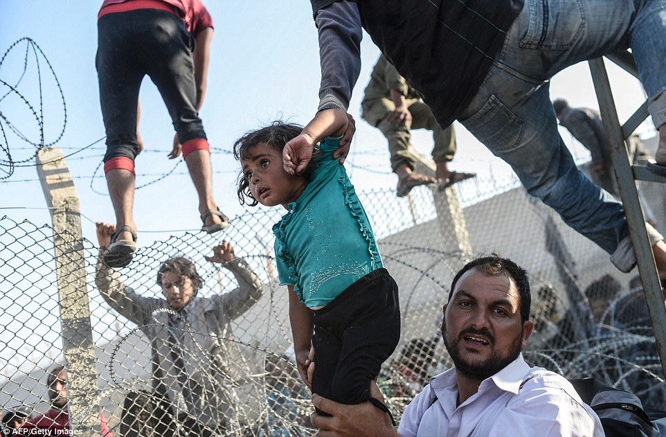 315708CF00000578-3452659-This_photo_shows_a_Syrian_child_fleeing_the_war_being_lifted_ove-a-1_1455813038303