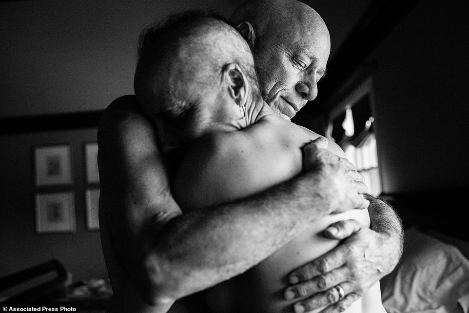In this image released by World Press Photo titled "A Life in Death" by photographer Nacy Borowick which won second prize Long Term Projects shows Howie and Laurel Borowick embrace in the bedroom of their home. In their 34- year marriage, they were diagnosed with stage-four cancer at the same time. New York, USA, March 8, 2013. A daughter photographs her own parents who were in parallel treatment for stage-four cancer, side by side. The project looks at love, life, and living, in the face of death. It honors their memory by focusing on their strength and love, both individually and together, and shares the story of their final chapters, within a year of each other. (Nancy Borowick, World Press Photo via AP)