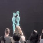 DOS PERSONAS SE BESAN DETRÁS DE UNA PANTALLA, CUANDO SE MUESTRAN AL PÚBLICO, ÉSTE SE QUEDA SIN PALABRAS