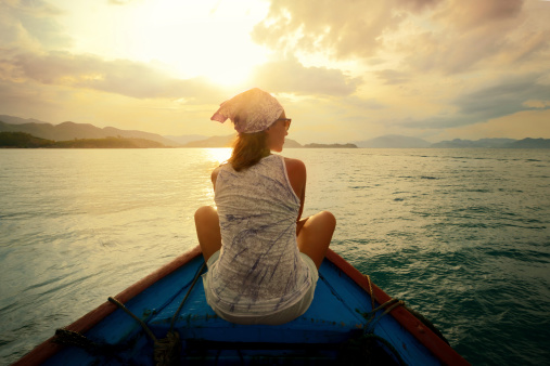 Woman traveling by boat at sunset among the islands.