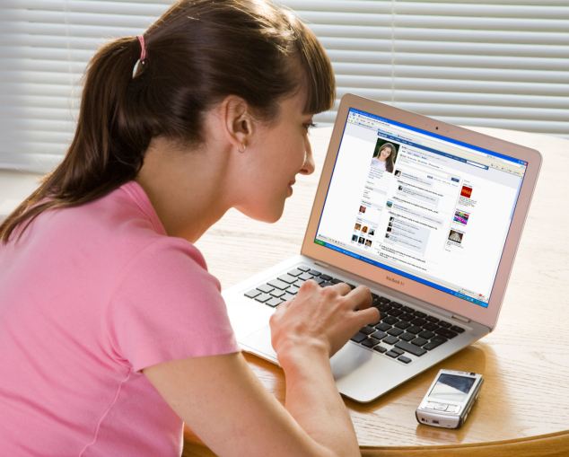 B84HCD young woman looking at Facebook website on laptop computer. Image shot 2008. Exact date unknown.