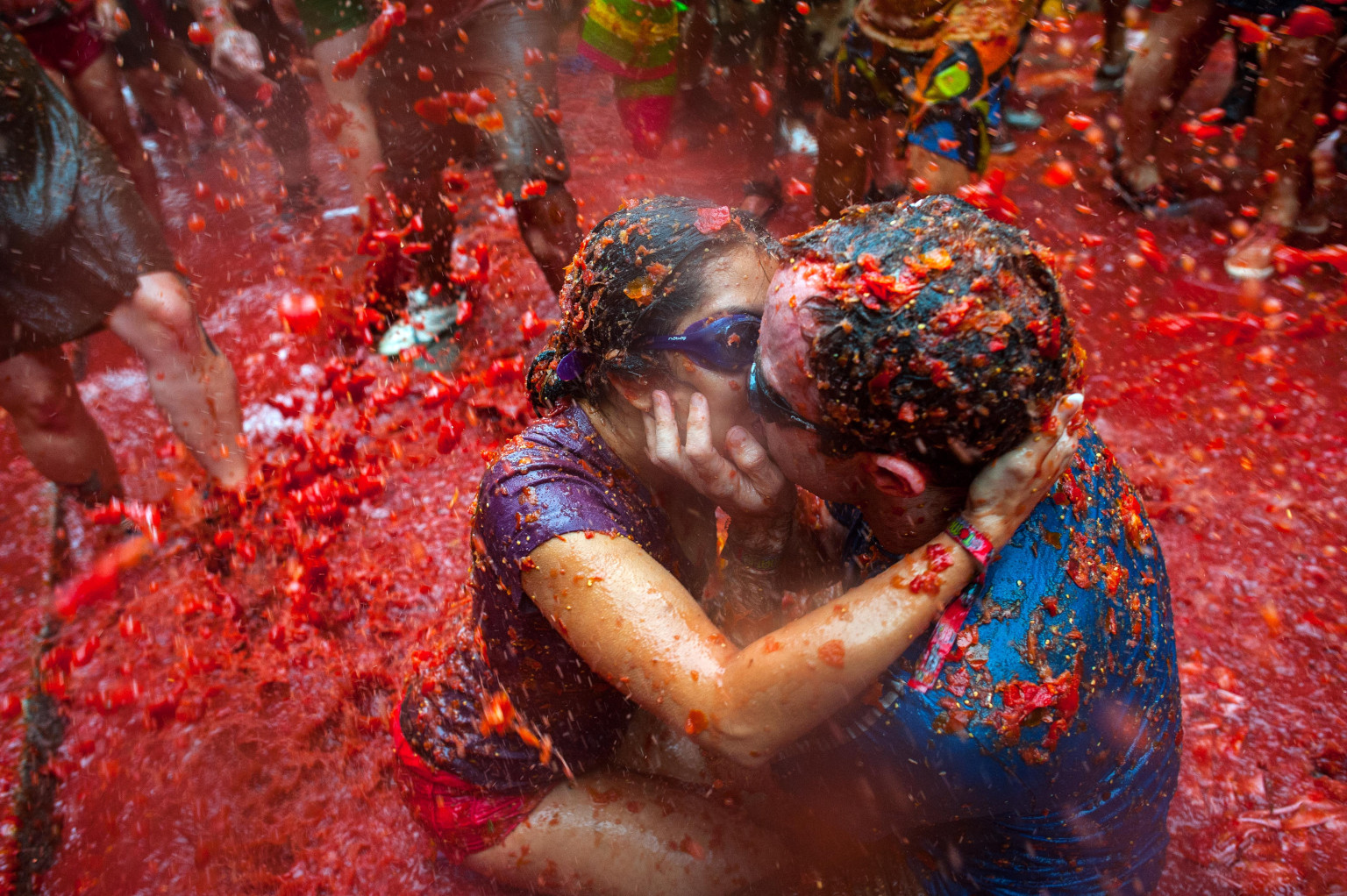 BUNOL, SPAIN - AUGUST 28: Two Revellers kiss each other covered in tomato pulp while participating the annual Tomatina festival on August 28, 2013 in Bunol, Spain. An estimated 20,000 people threw 130 tons of ripe tomatoes in the world's biggest tomato fight held annually in this Spanish Mediterranean town. (Photo by David Ramos/Getty Images)