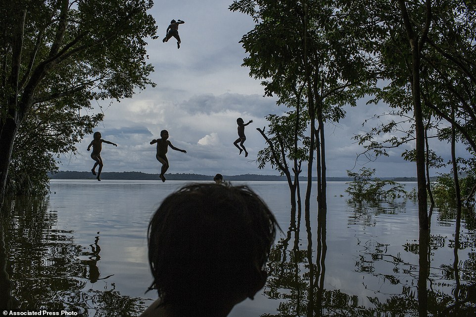 In this image released by World Press Photo titled "Amazon's Munduruku Tribe" by photographer Mauricio Lima for The New York Times which won second prize in the Daily Life singles category shows indigenous Munduruku children playing in the Tapajos river in the tribal area of Sawre Muybu, Itaituba, Brazil, Feb. 10, 2015. The tribesmen of the Munduruku, who for centuries have sanctified the Tapajos River on which their villages sit, are fighting for survival. Brazils government plans to flood much of their land to build a $9.9 billion hydroelectric dam, the Sao Luiz do Tapajos, as part of a wider energy strategy across the Amazon rainforest. (Mauricio Lima/The New York Times, World Press Photo via AP)