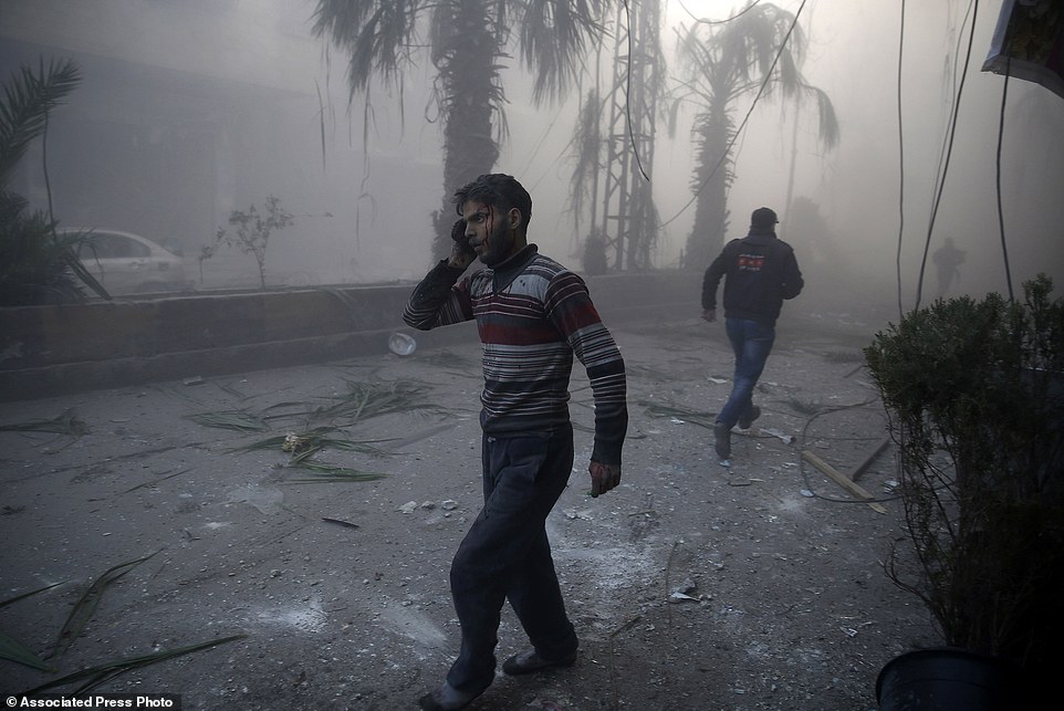 In this image released by World Press Photo titled "Aftermath of Airstrikes in Syria" by photographer Sameer Al-Doumy for AFP which won the first prize in the Spot News stories category shows a wounded man walking out of a dust cloud following reported airstrikes in the town of Hamouria, Syria, Dec. 9, 2015.(Sameer Al-Doumy/AFP, World Press Photo via AP)